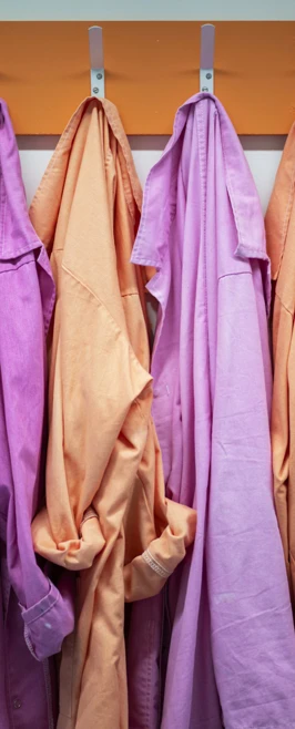 Four vibrant lab coats in shades of orange and pink hang neatly on hooks, just waiting for the next group of scientists to suit up Four vibrant lab coats in shades of orange and pink hang neatly on hooks, just waiting for the next group of scientists to suit up